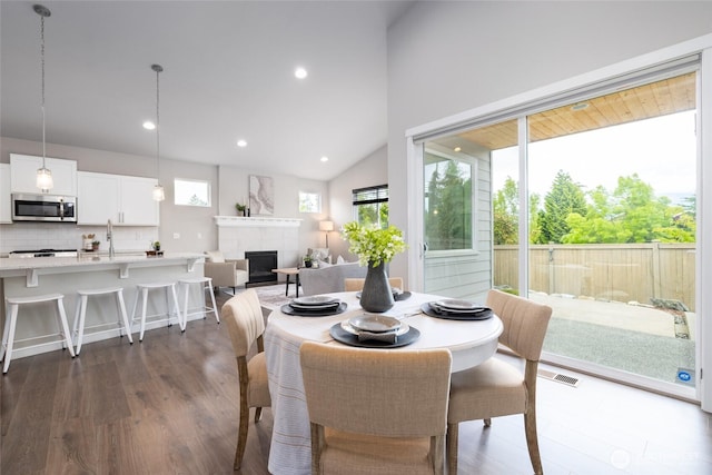 dining area featuring dark wood finished floors, a fireplace, lofted ceiling, and recessed lighting