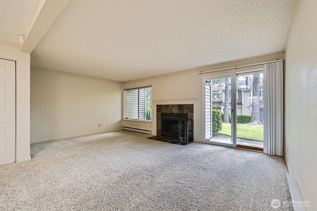 23723 12th Pl S Unit 2005, Des Moines, WA 98198 - unfurnished living room featuring baseboard heating, carpet flooring, a tile fireplace, a textured ceiling, and baseboards
