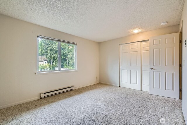 23723 12th Pl S Unit 2005, Des Moines, WA 98198 - unfurnished bedroom with a baseboard radiator, carpet, a textured ceiling, a closet, and baseboards