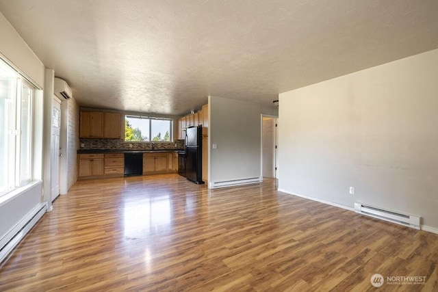 301 E Silberhorn Rd, Sequim, WA 98382 - kitchen with black appliances, a baseboard heating unit, open floor plan, dark countertops, and an AC wall unit