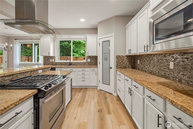 6503 Wrangler Dr SE, Tumwater, WA 98501 - kitchen with appliances with stainless steel finishes, island exhaust hood, a sink, light wood-style flooring, and white cabinetry