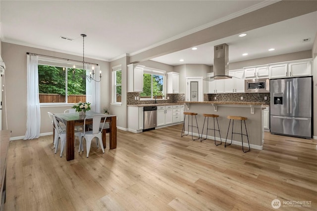 6503 Wrangler Dr SE, Tumwater, WA 98501 - kitchen featuring stainless steel appliances, island range hood, a kitchen bar, crown molding, and white cabinets