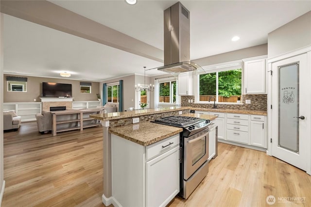6503 Wrangler Dr SE, Tumwater, WA 98501 - kitchen featuring gas stove, island range hood, a chandelier, open floor plan, and light wood-type flooring