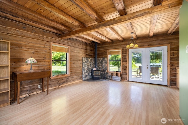 unfurnished living room featuring french doors, a wood stove, wood ceiling, wood finished floors, and beamed ceiling