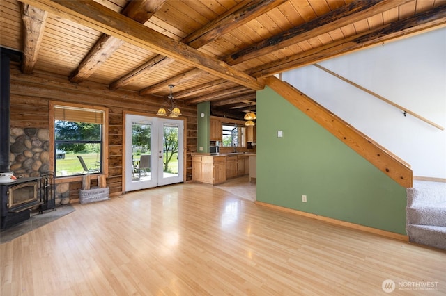 unfurnished living room featuring a wood stove, wooden ceiling, light wood-style floors, stairs, and french doors