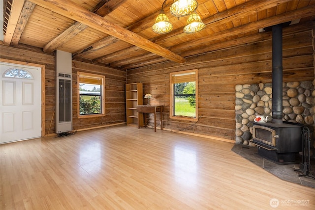 unfurnished living room featuring wood ceiling, a wood stove, beamed ceiling, wood finished floors, and wood walls