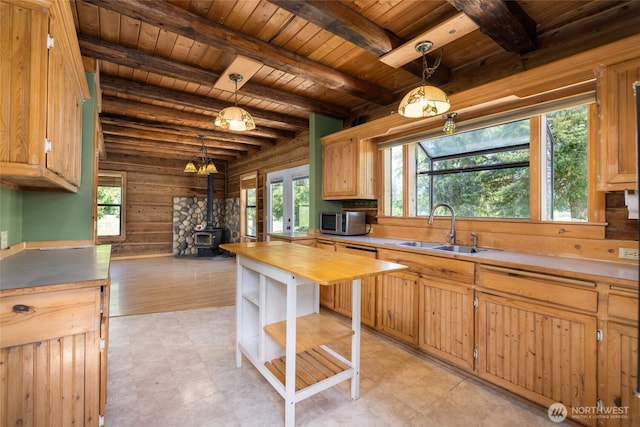 kitchen with a sink, stainless steel microwave, wooden ceiling, a wood stove, and butcher block counters