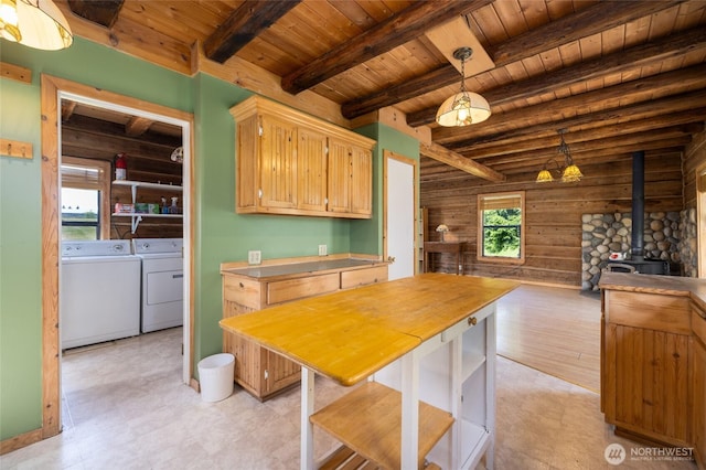 kitchen with washer and clothes dryer, wooden ceiling, a wood stove, wooden walls, and beam ceiling