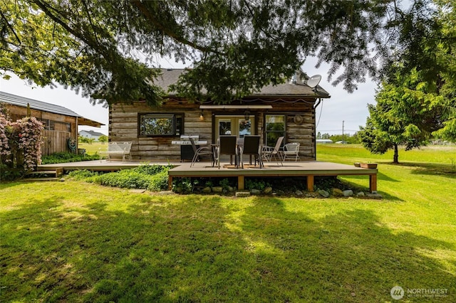 rear view of property featuring a wooden deck and a lawn