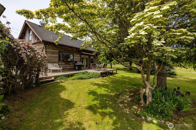 view of green lawn featuring french doors and a deck