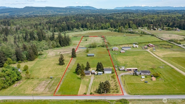 aerial view of sparsely populated area with a heavily wooded area, mountains, and property parcel outlined