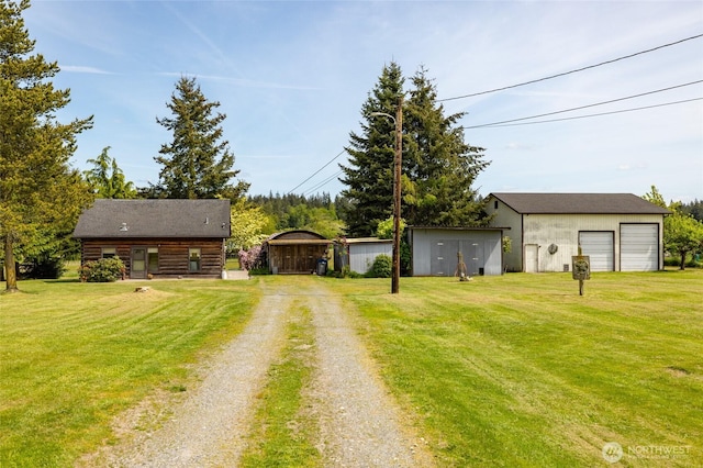 view of front of home featuring driveway, an outdoor structure, a front lawn, and a detached garage
