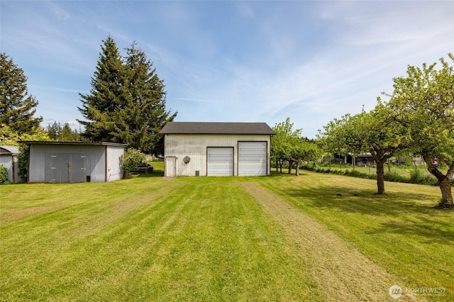 view of green lawn with an outdoor structure and a garage