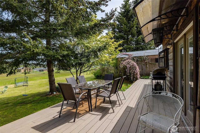 wooden deck with outdoor dining space, a yard, and area for grilling