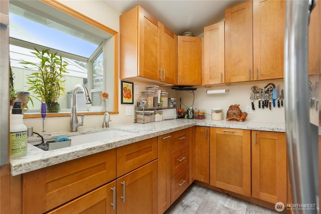 4808 38th Ave SW, Seattle, WA 98126 - kitchen with light wood-type flooring, a sink, light stone countertops, and brown cabinetry
