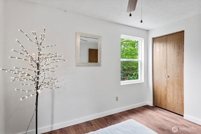 17910 Spruce Way, Lynnwood, WA 98037 - unfurnished bedroom with wood finished floors, baseboards, a closet, a textured ceiling, and a ceiling fan
