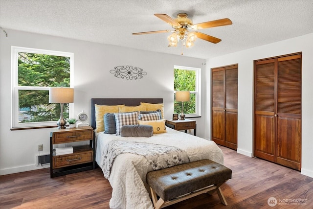 17910 Spruce Way, Lynnwood, WA 98037 - bedroom featuring two closets, a textured ceiling, wood finished floors, baseboards, and a ceiling fan