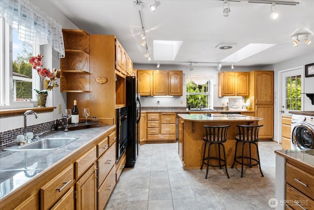 17910 Spruce Way, Lynnwood, WA 98037 - kitchen featuring rail lighting, a sink, a skylight, and washer / dryer