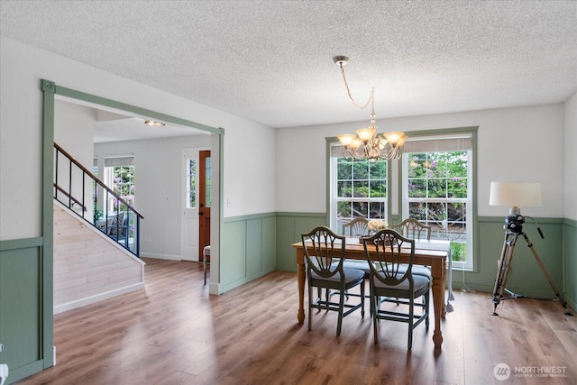 17910 Spruce Way, Lynnwood, WA 98037 - dining space with a chandelier, a textured ceiling, wood finished floors, a wainscoted wall, and stairway