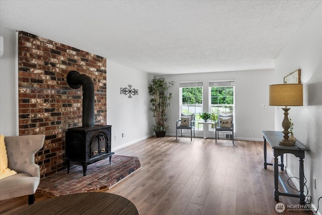 17910 Spruce Way, Lynnwood, WA 98037 - living room featuring a wood stove, a textured ceiling, baseboards, and wood finished floors