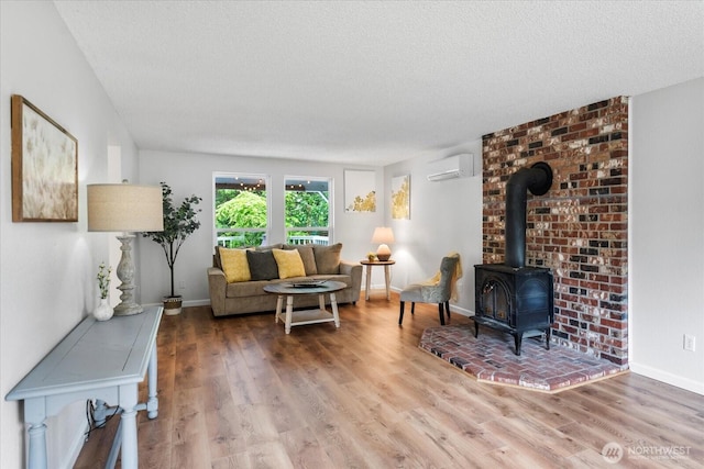 17910 Spruce Way, Lynnwood, WA 98037 - living area featuring a wall mounted AC, a wood stove, wood finished floors, a textured ceiling, and baseboards