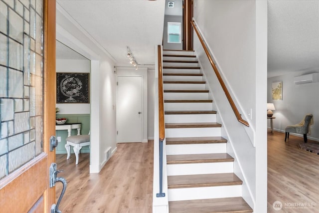 17910 Spruce Way, Lynnwood, WA 98037 - staircase featuring an AC wall unit, a textured ceiling, wood finished floors, track lighting, and baseboards