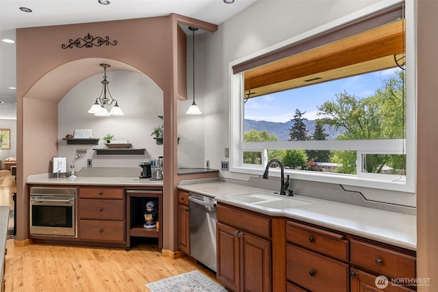 2720 NW Cascade Ave, East Wenatchee, WA 98802 - kitchen featuring stainless steel appliances, a sink, light wood-style flooring, brown cabinets, and hanging light fixtures