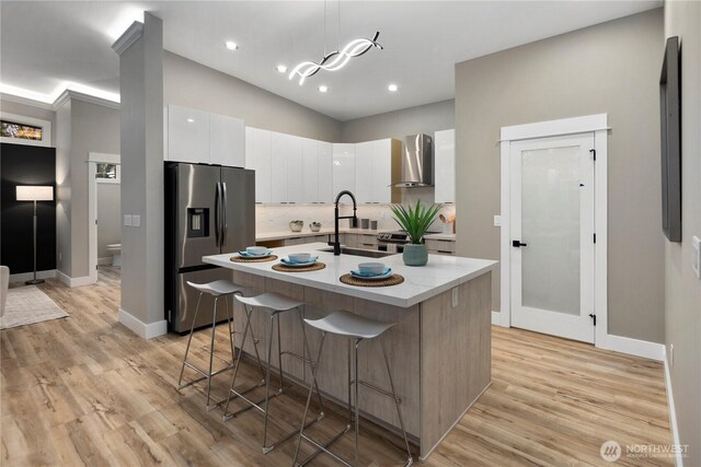 16250 SE Lake Moneysmith, Auburn, WA 98092 - kitchen featuring appliances with stainless steel finishes, wall chimney exhaust hood, a sink, white cabinetry, and a kitchen breakfast bar