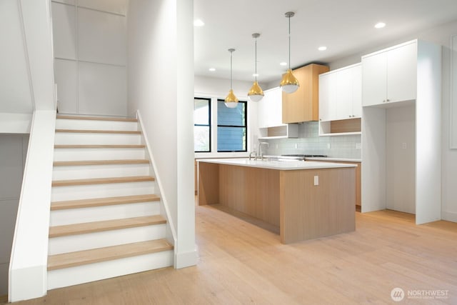 706 N 59th St, Seattle, WA 98103 - kitchen with decorative backsplash, light countertops, an island with sink, light wood-style floors, and modern cabinets