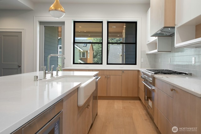 706 N 59th St, Seattle, WA 98103 - kitchen with light countertops, open shelves, tasteful backsplash, a sink, and light wood-type flooring