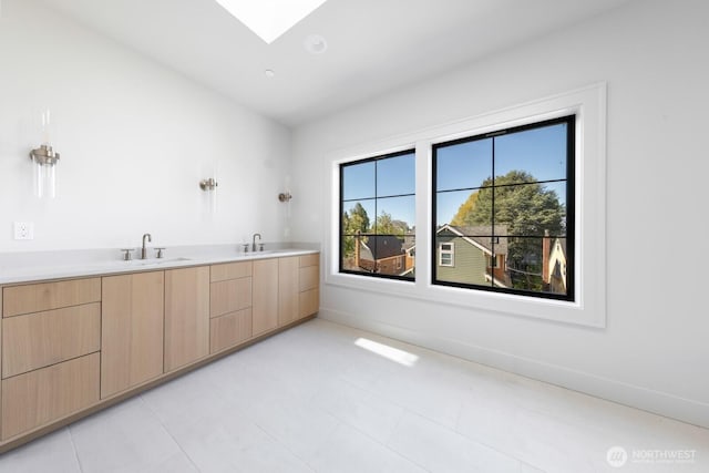 706 N 59th St, Seattle, WA 98103 - bathroom with a skylight, double vanity, and baseboards