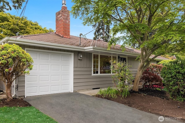 view of front facade with a garage, a chimney, crawl space, and asphalt driveway