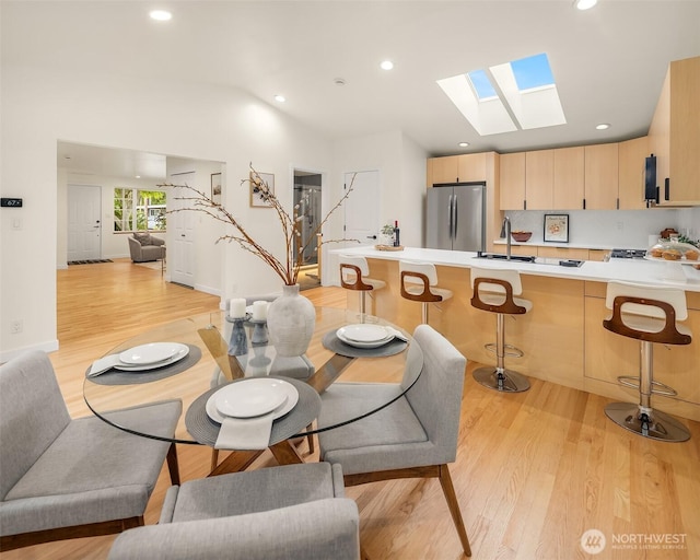 dining space with a skylight, light wood-type flooring, recessed lighting, and vaulted ceiling