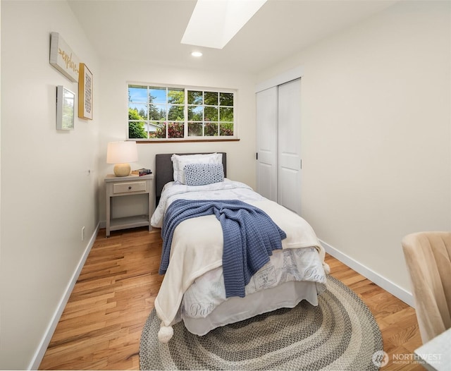 bedroom with a skylight, baseboards, light wood-style floors, a closet, and recessed lighting