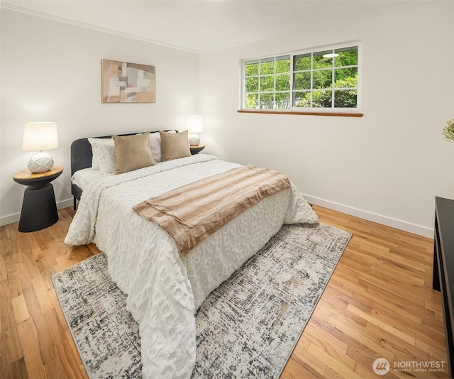 bedroom featuring baseboards, wood finished floors, and crown molding