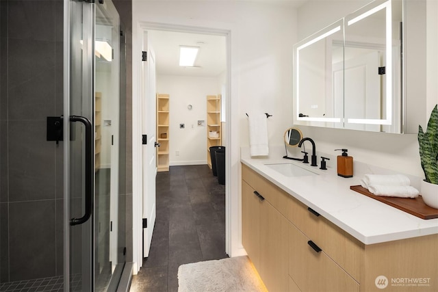 bathroom featuring a shower stall, a walk in closet, vanity, and baseboards