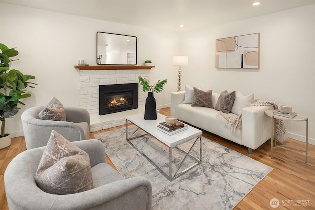 living area featuring recessed lighting, wood finished floors, baseboards, and a stone fireplace