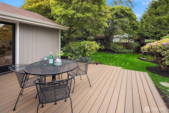 deck with outdoor dining area, a storage unit, and an outdoor structure