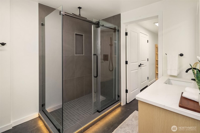 full bath with a stall shower, vanity, and baseboards