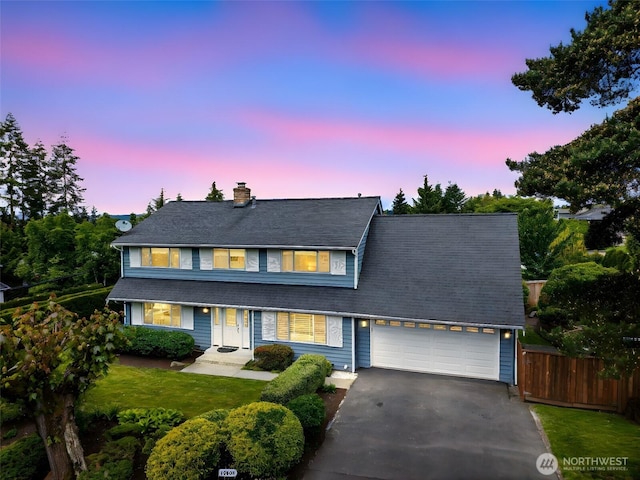 traditional-style house featuring asphalt driveway, fence, a chimney, and an attached garage