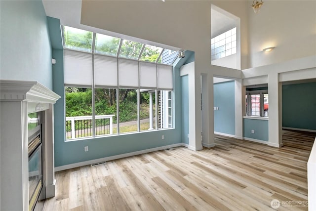 17634 118th Ave SE, Renton, WA 98058 - unfurnished living room with a glass covered fireplace, wood finished floors, baseboards, and a high ceiling