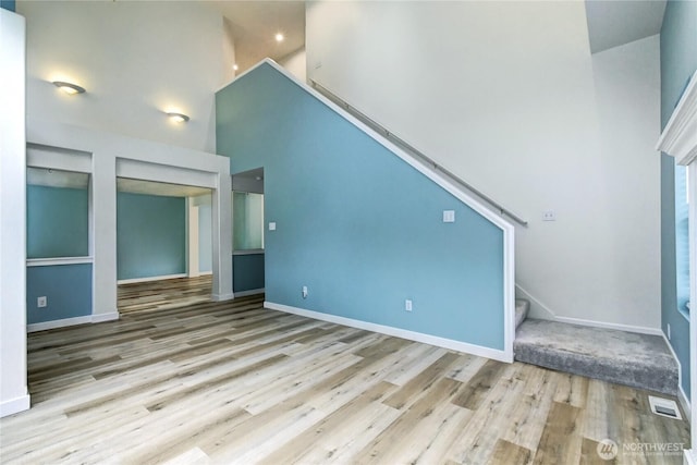 17634 118th Ave SE, Renton, WA 98058 - unfurnished living room with a towering ceiling, stairs, wood finished floors, and baseboards