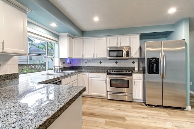 17634 118th Ave SE, Renton, WA 98058 - kitchen with stainless steel appliances, a sink, white cabinets, light wood-type flooring, and backsplash