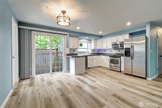 17634 118th Ave SE, Renton, WA 98058 - kitchen featuring appliances with stainless steel finishes, dark countertops, light wood-style floors, white cabinetry, and tasteful backsplash