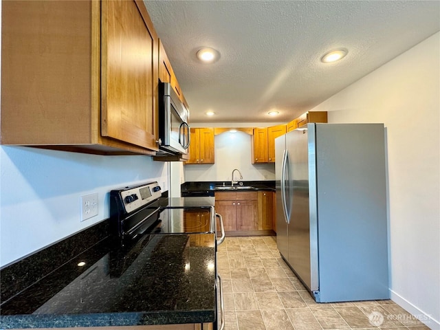 8312 121st St SW, Lakewood, WA 98498 - kitchen with stainless steel appliances, a sink, brown cabinets, dark stone countertops, and a textured ceiling