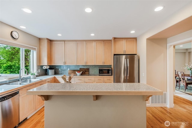 11120 NE 106th Pl, Kirkland, WA 98033 - kitchen featuring appliances with stainless steel finishes, a sink, light brown cabinets, a breakfast bar area, and recessed lighting