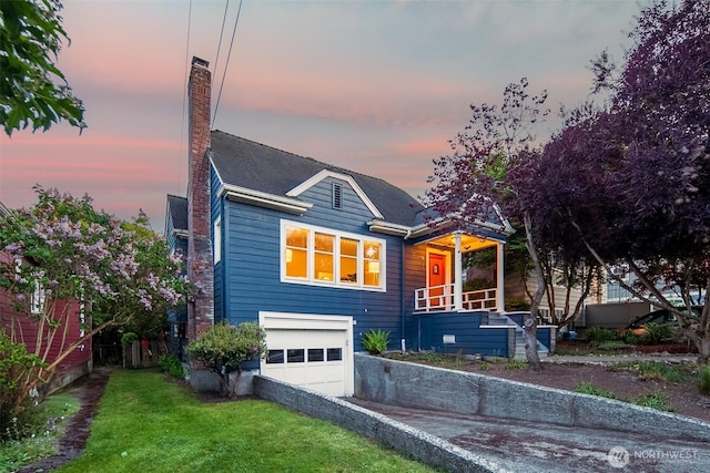 view of front facade featuring a garage, driveway, a yard, a chimney, and roof with shingles