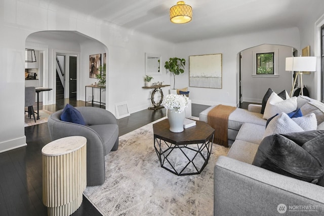 living room with arched walkways, hardwood / wood-style floors, and baseboards