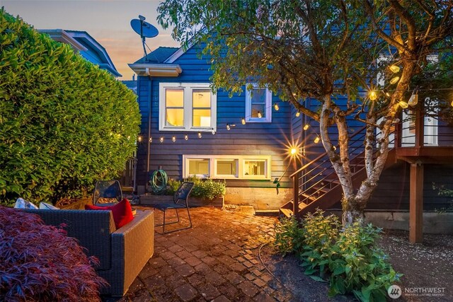 back of property at dusk with a patio and stairway