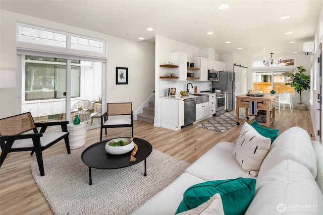 living area featuring healthy amount of natural light, light wood finished floors, a wall mounted AC, a chandelier, and recessed lighting